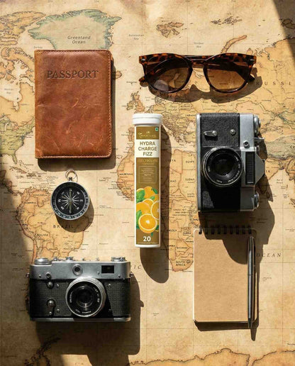 Travel-themed items including a passport, sunglasses, cameras, and a tube of cream on a world map background.