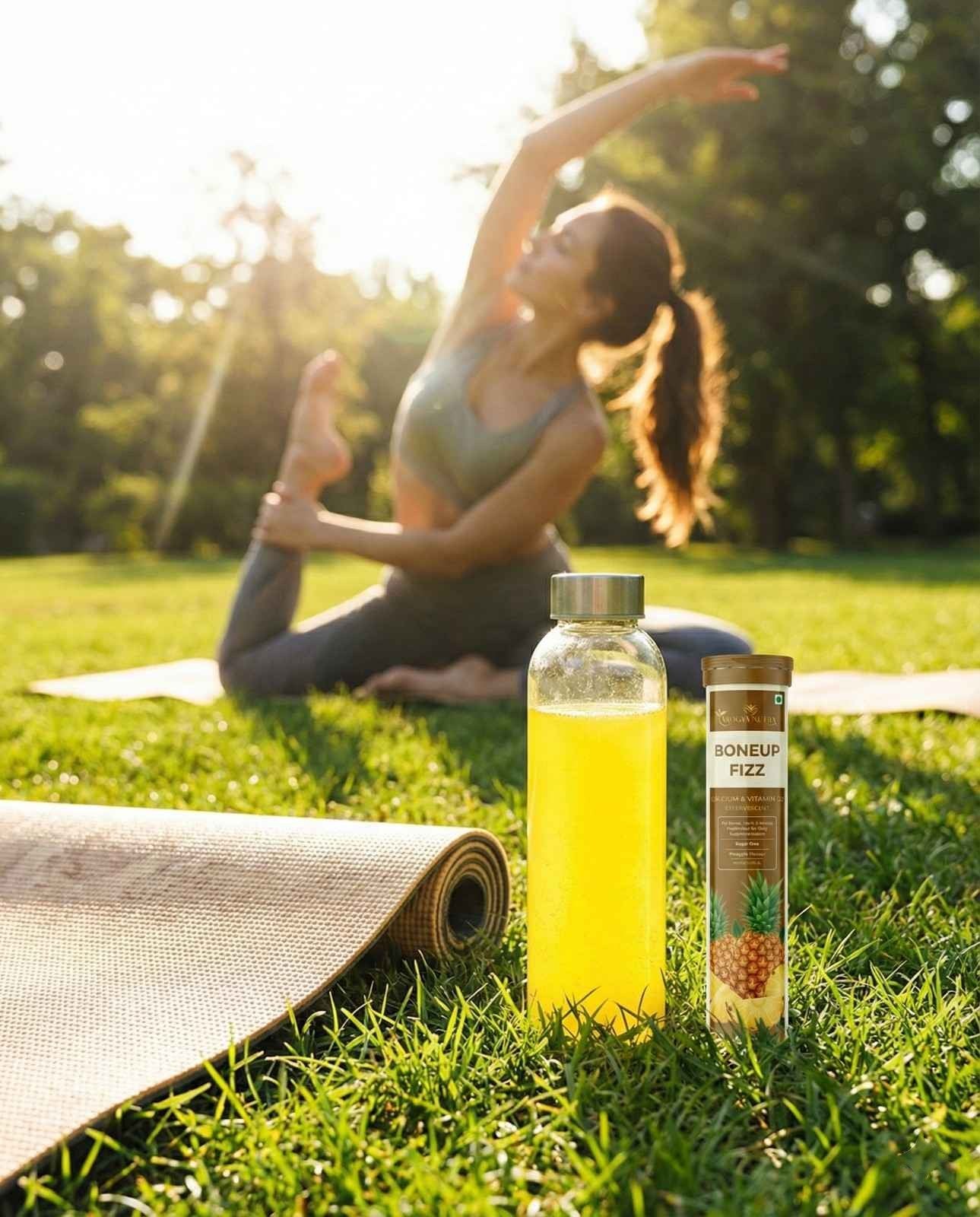 Woman practicing yoga outdoors with a bottle of juice and a box on the grass.